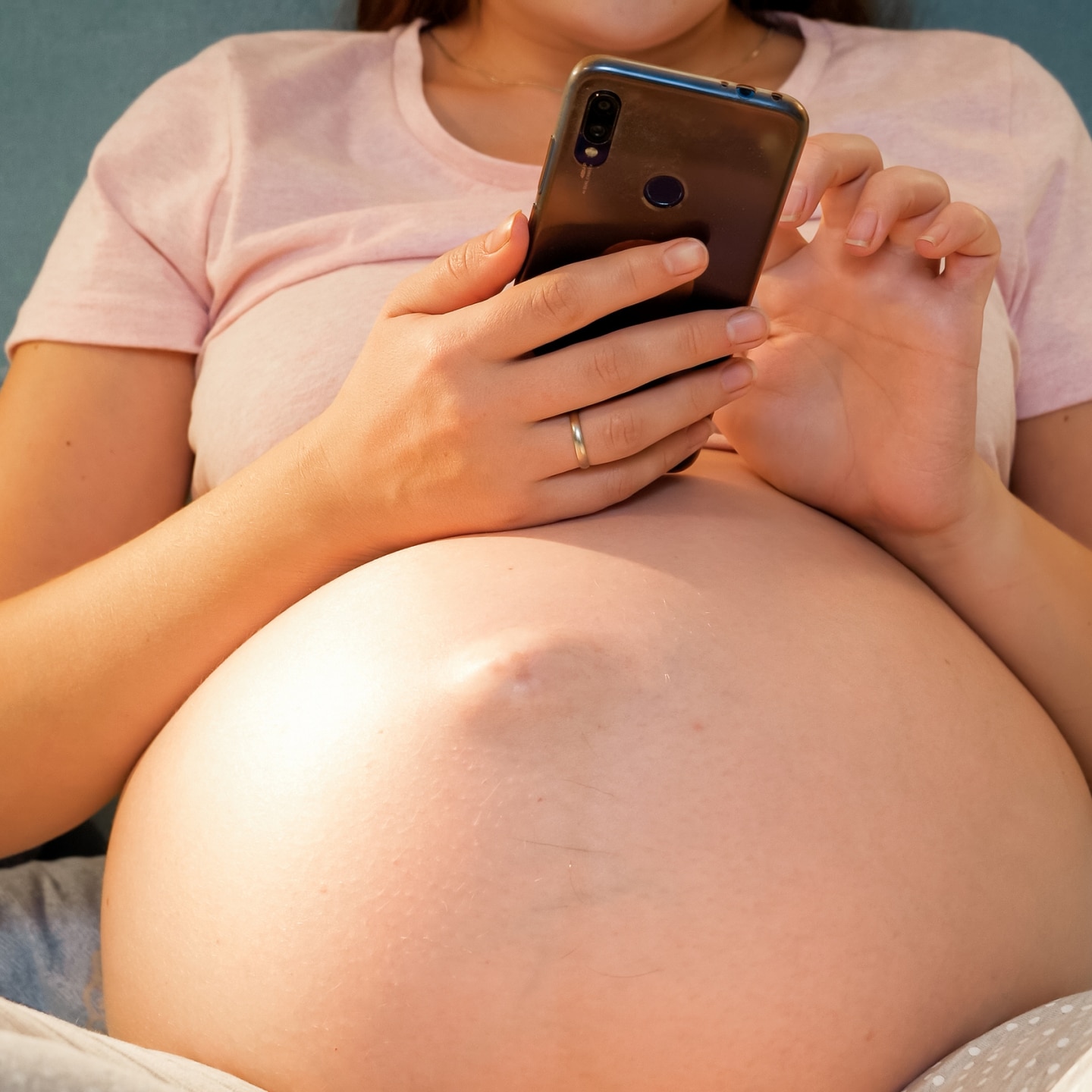 Schwangere hält Handy in der Hand