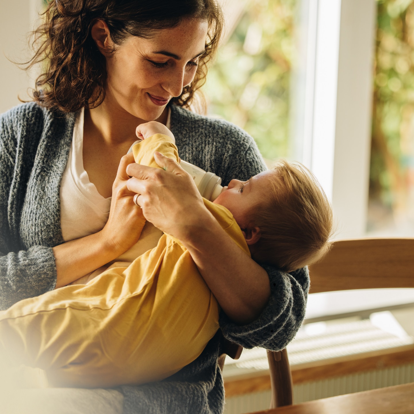 Caring mother feeding milk from bottle to her baby