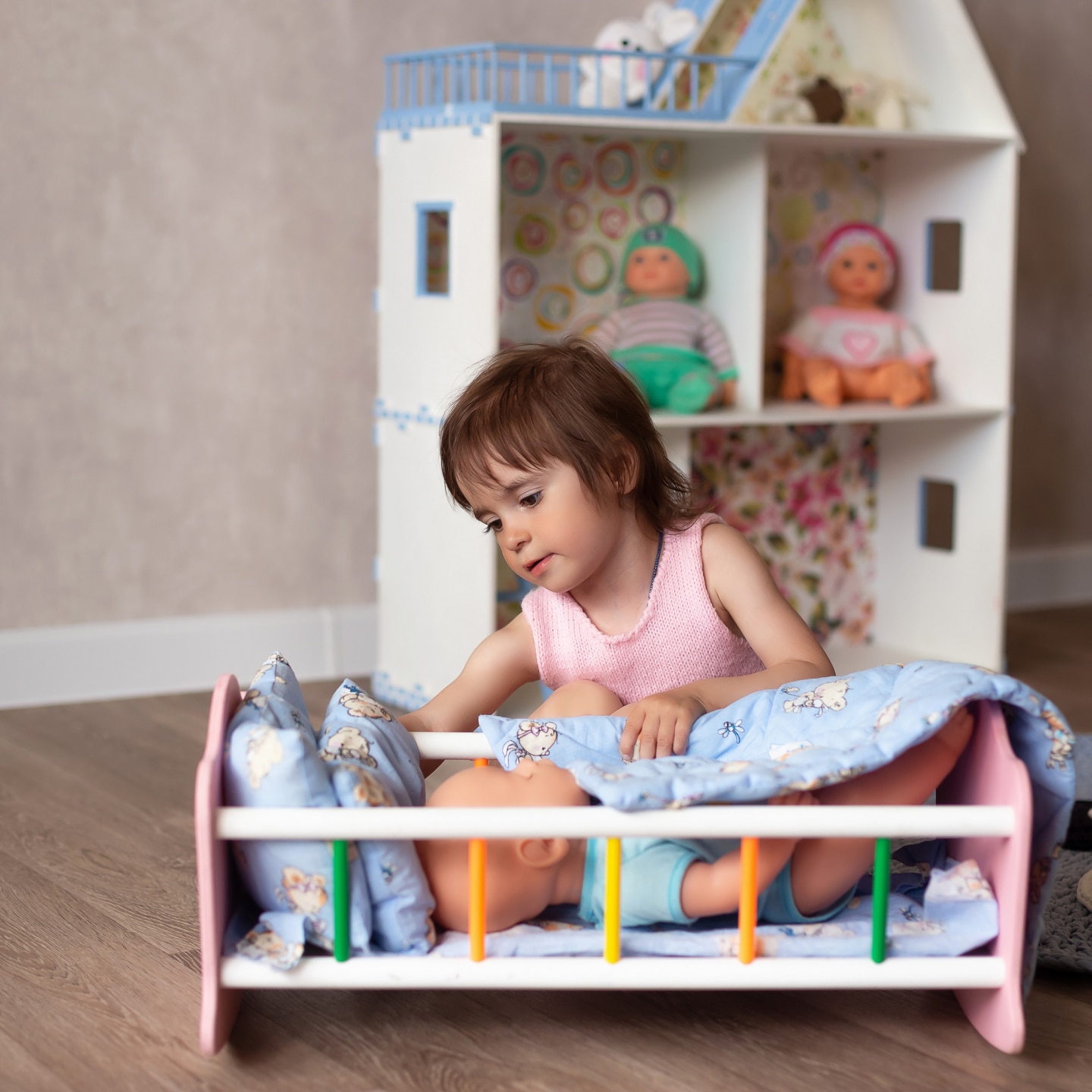 Cute little girl is playing with a doll at home