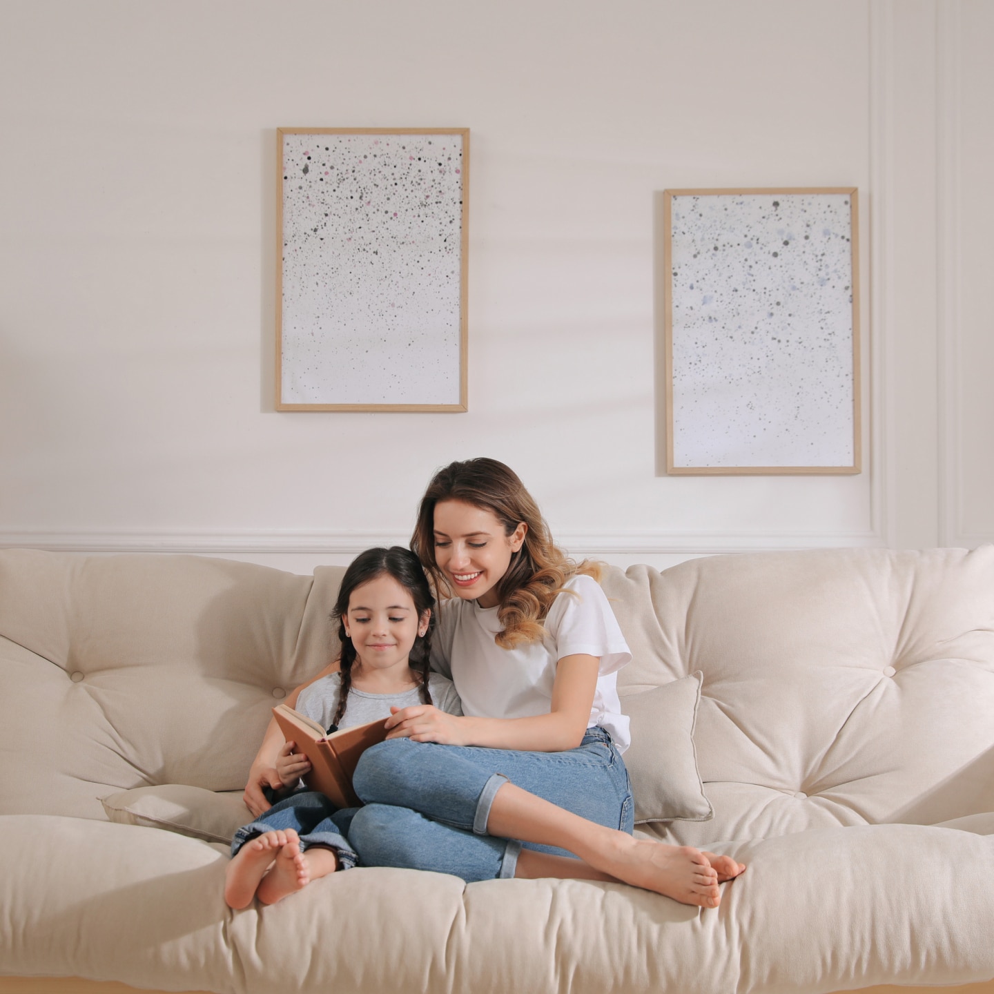 Mother and daughter reading book on sofa at home