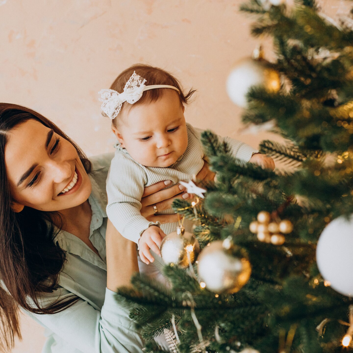 Mutter und Baby schmücken den Weihnachtsbaum