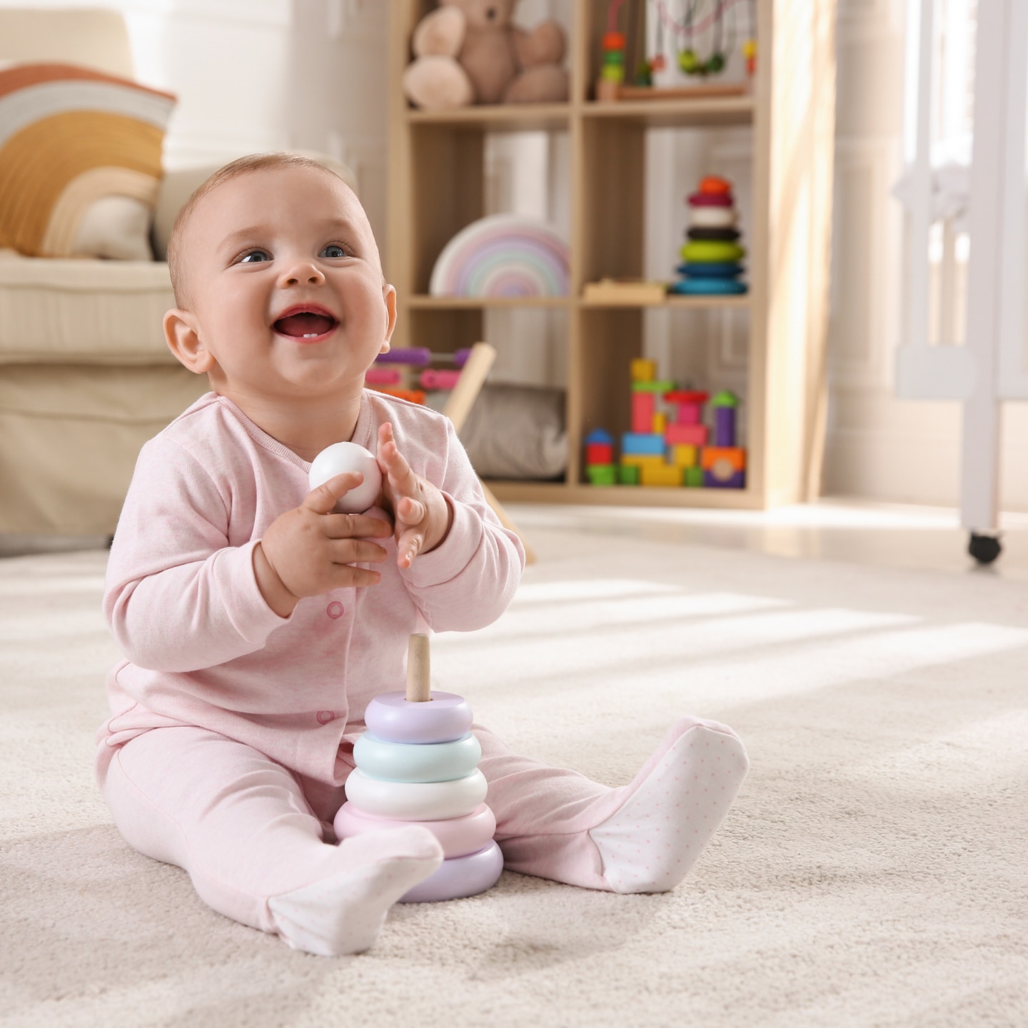 Cute baby girl playing with toy pyramid on floor at home