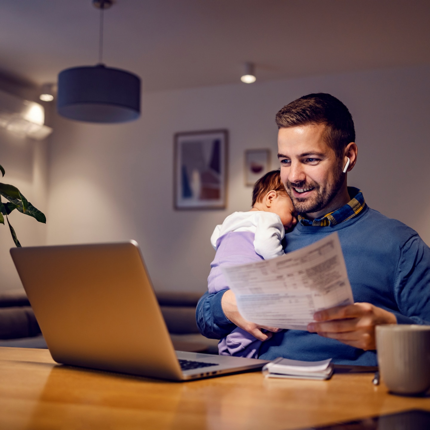 young dad works from home holds his sleepy baby girl in his hands