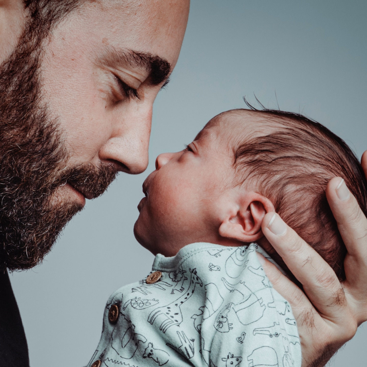 portrait of man looking at his newborn son with loving expression