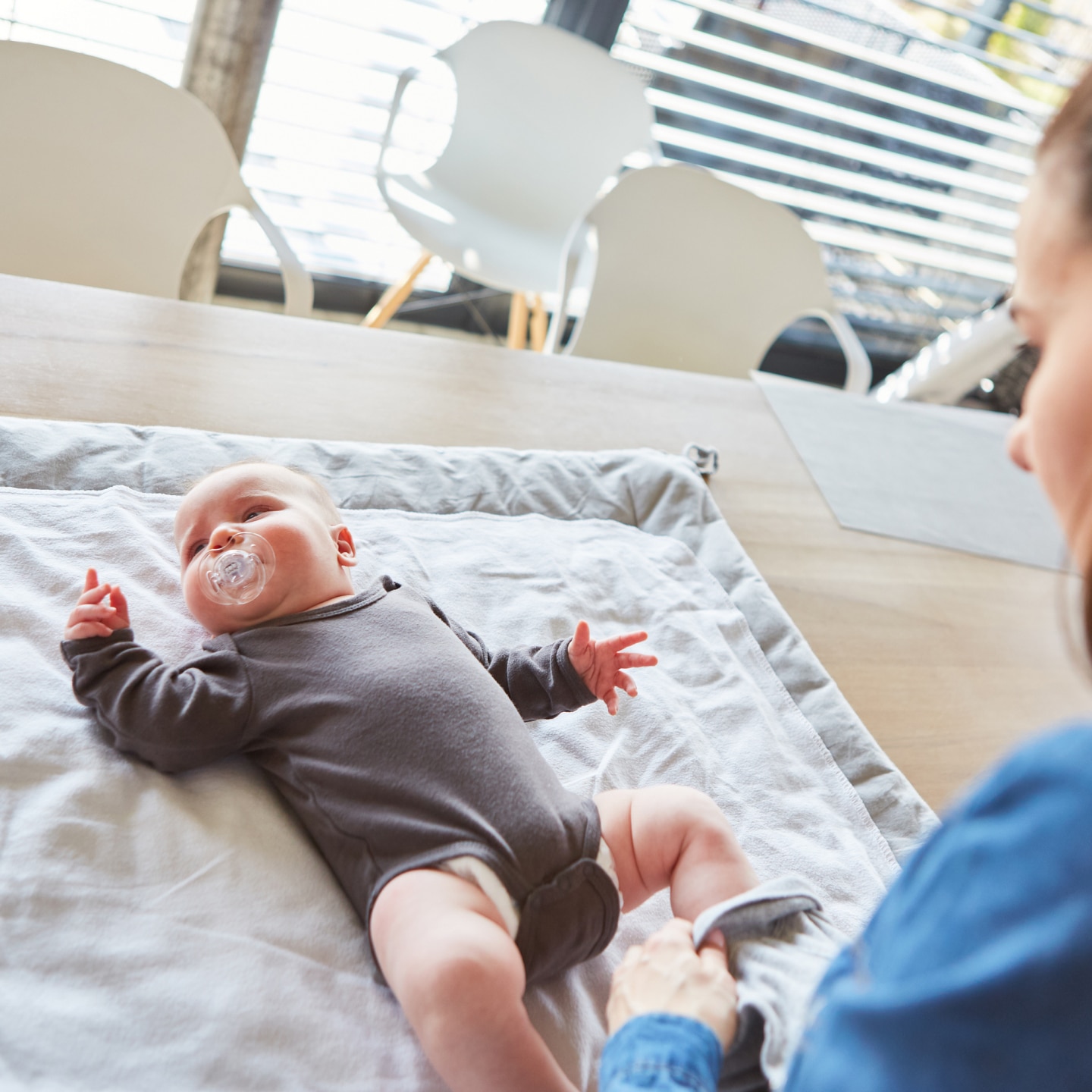 Baby liegt im Strampelanzug auf dem Wickeltisch