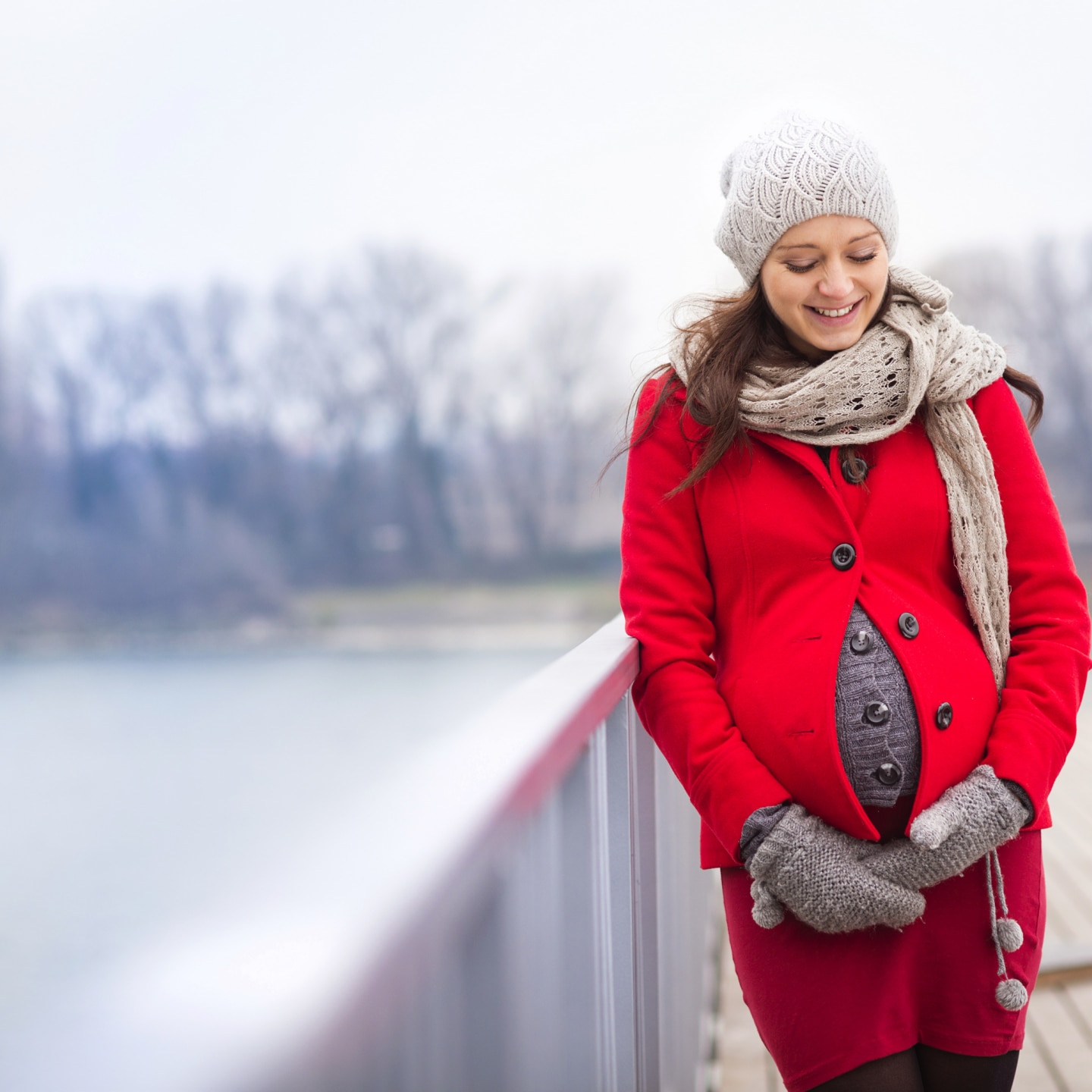 Schwangere Frau am See im Winter