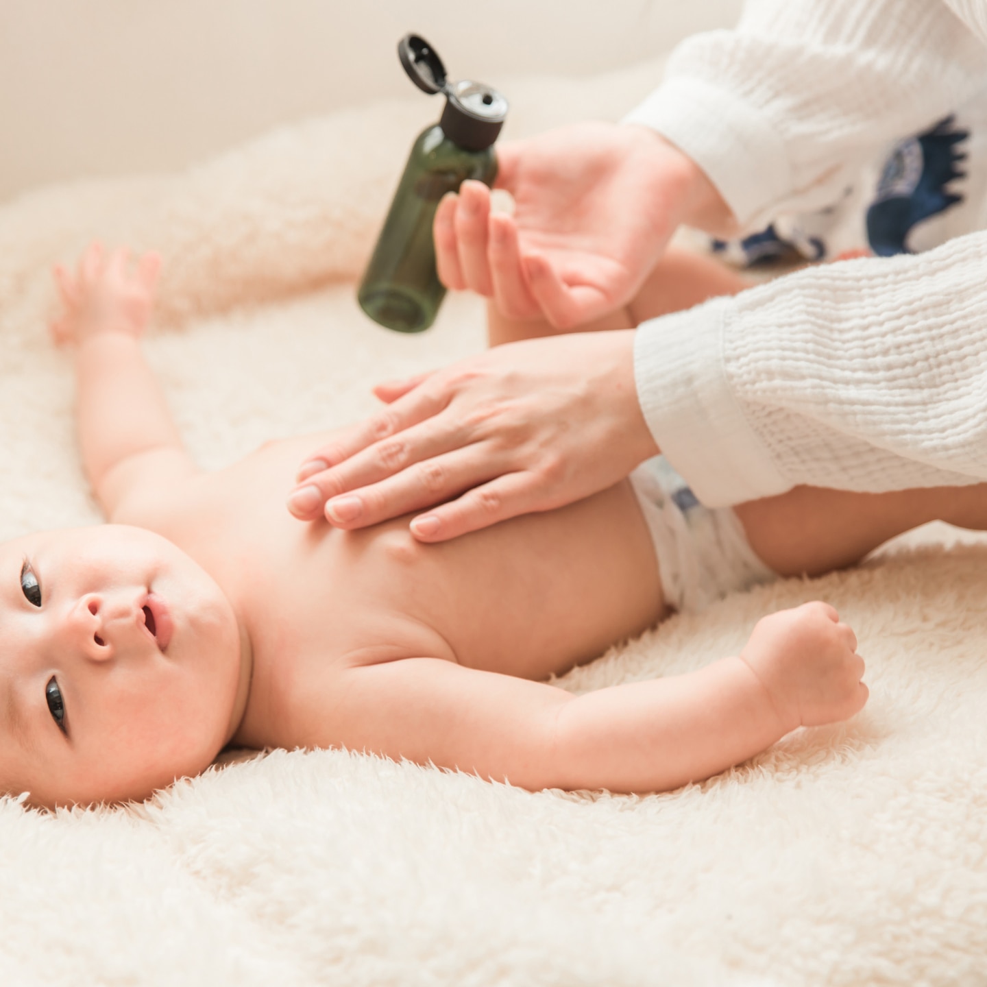 Mutter schmiert ihn mit Babyöl ein 