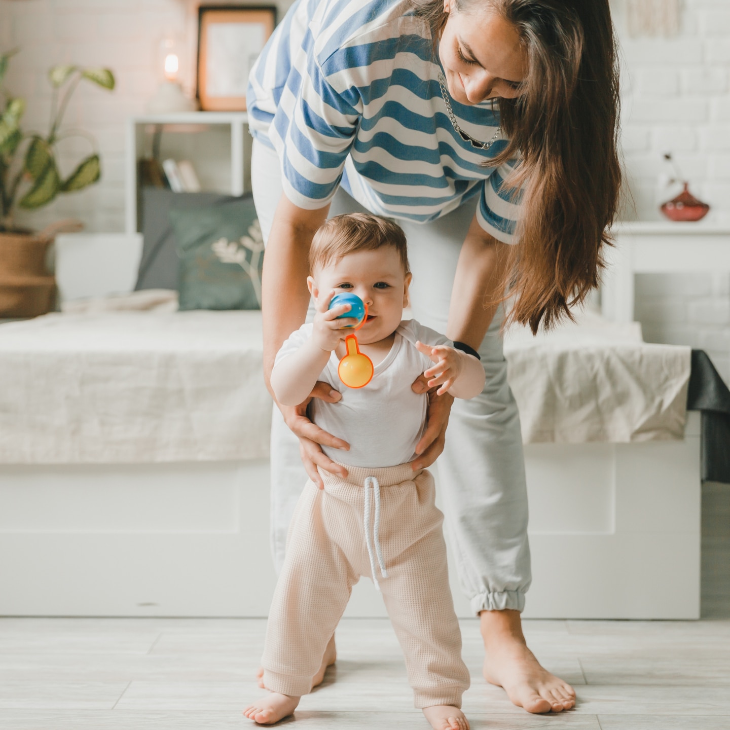little child learns to walk with the help of mother at home