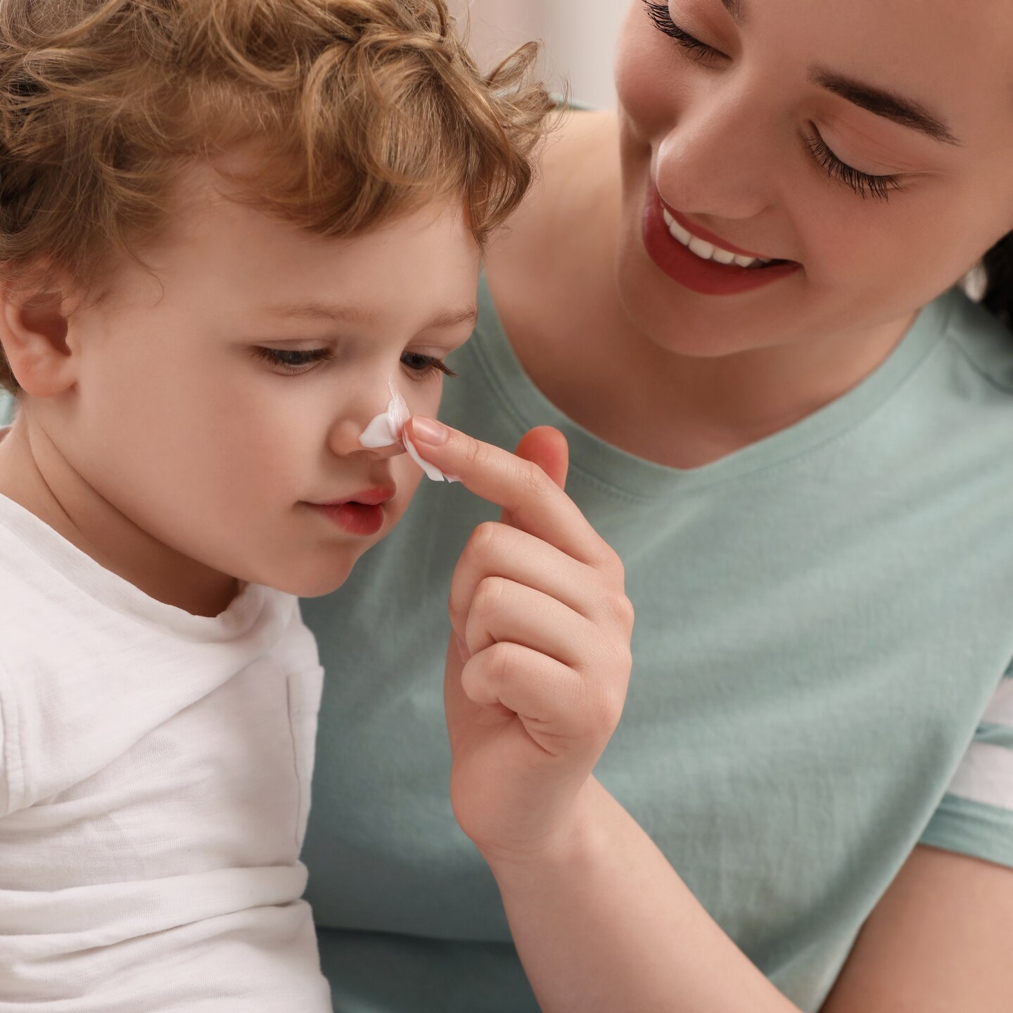 Mutter cremt Nase ihres Sohnes ein