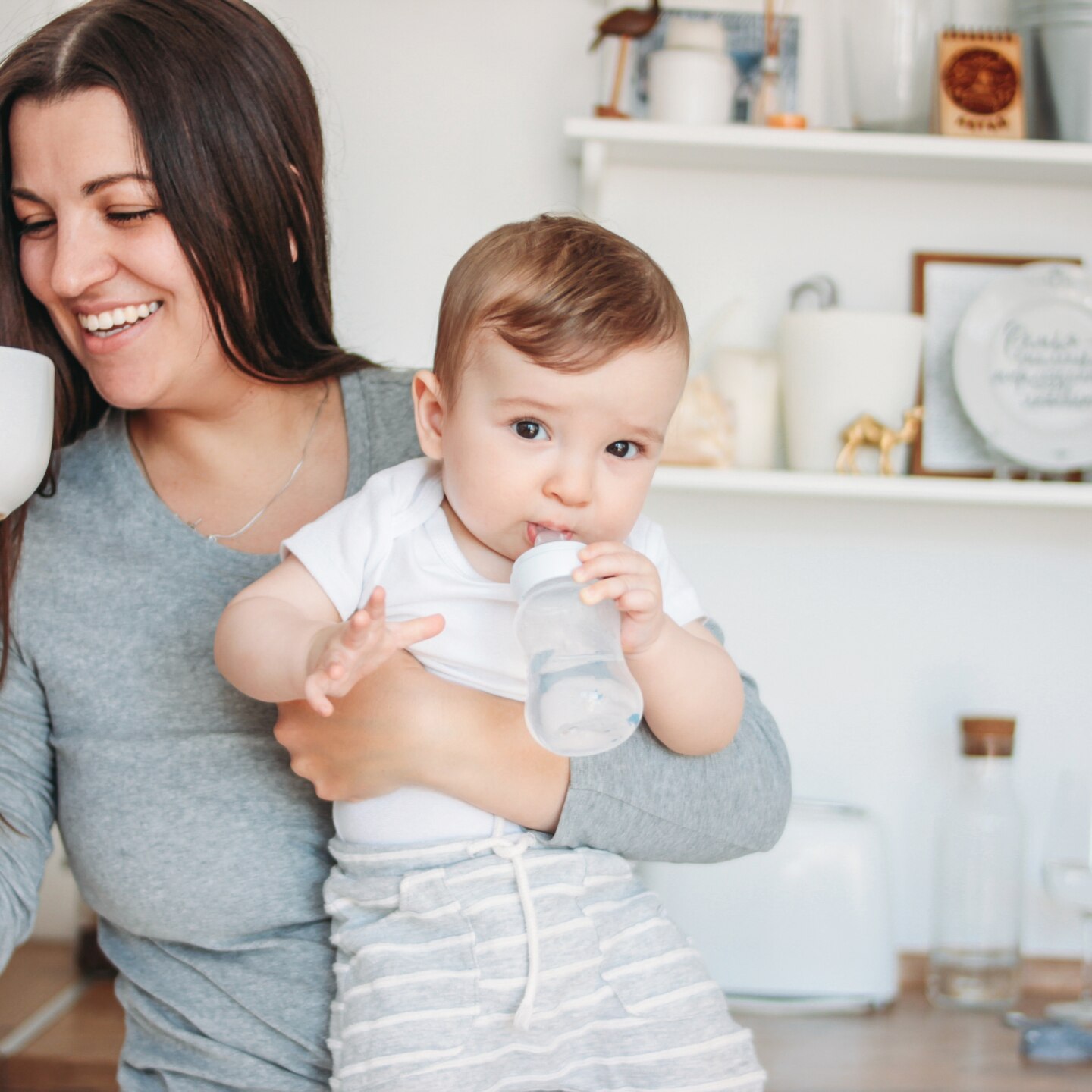 Mama mit Tasse und Baby im Arm