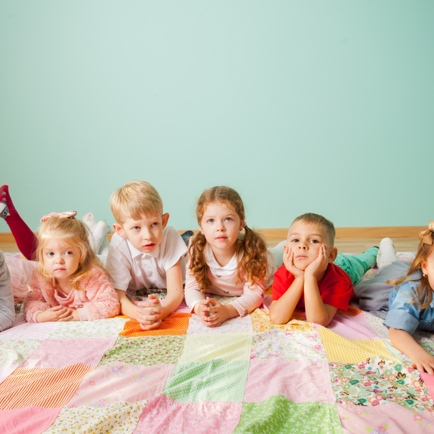 viele kinder liegen nebeneinander auf dem einer decke auf dem boden