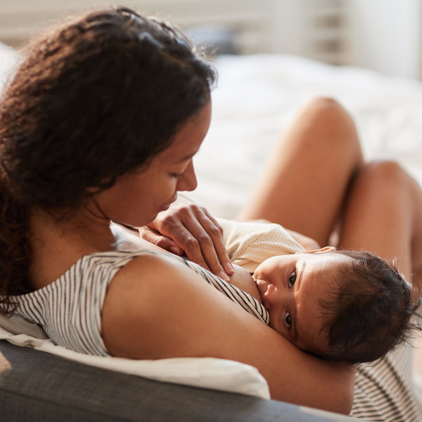 mama sitzt auf dem bett und stillt ihr baby