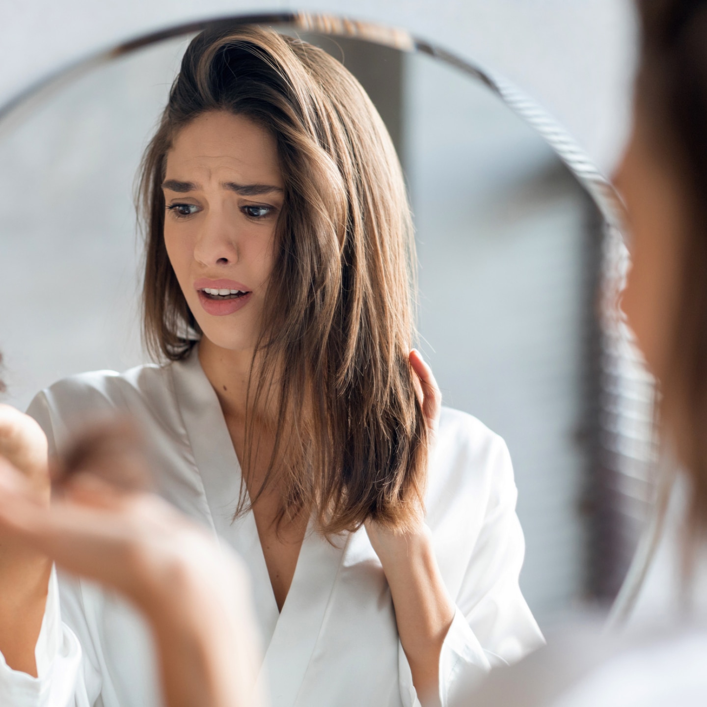 frau schaut erschrocken auf ein haarbündel in ihrer hand