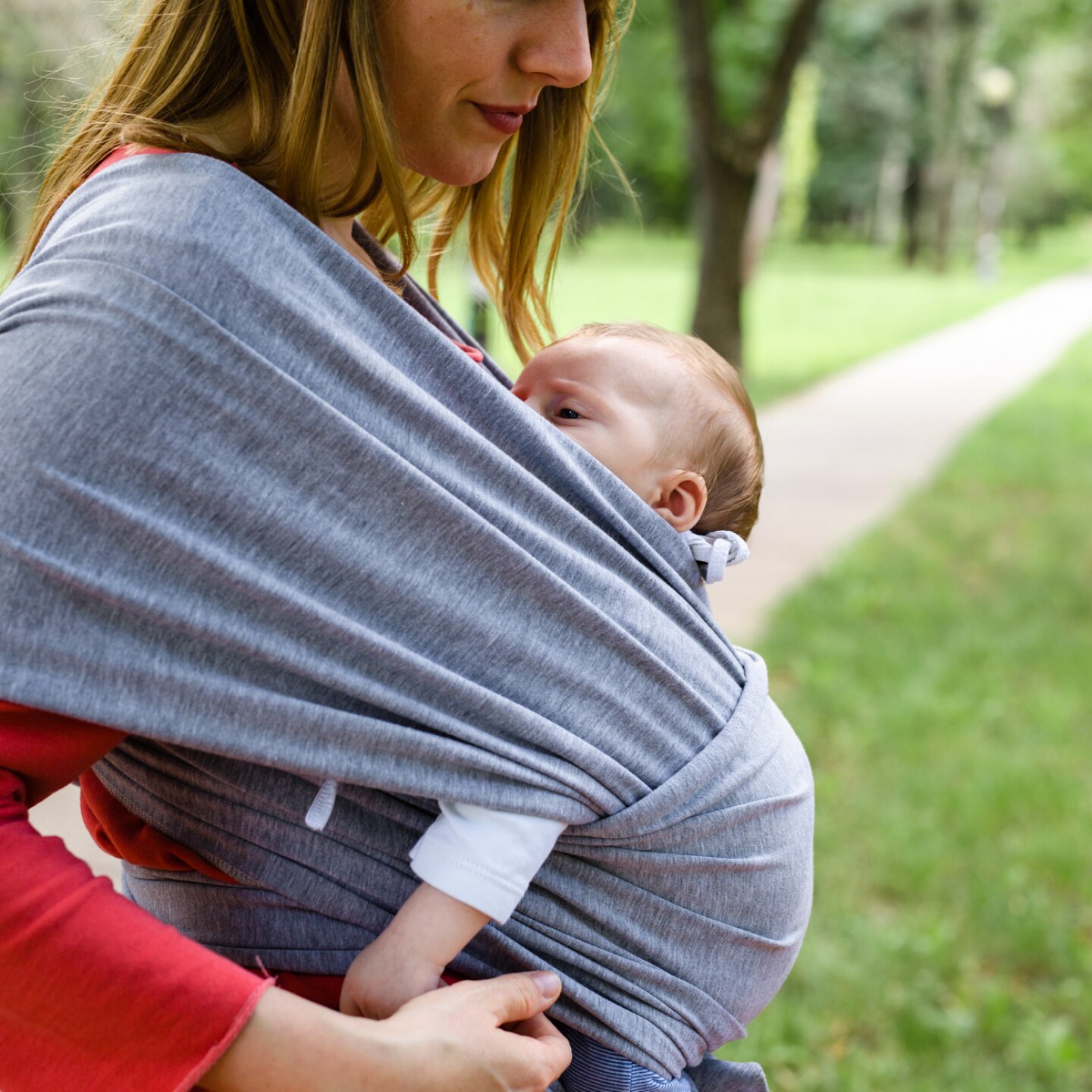 mutter-trägt-baby-mit-tragetuch-im-park