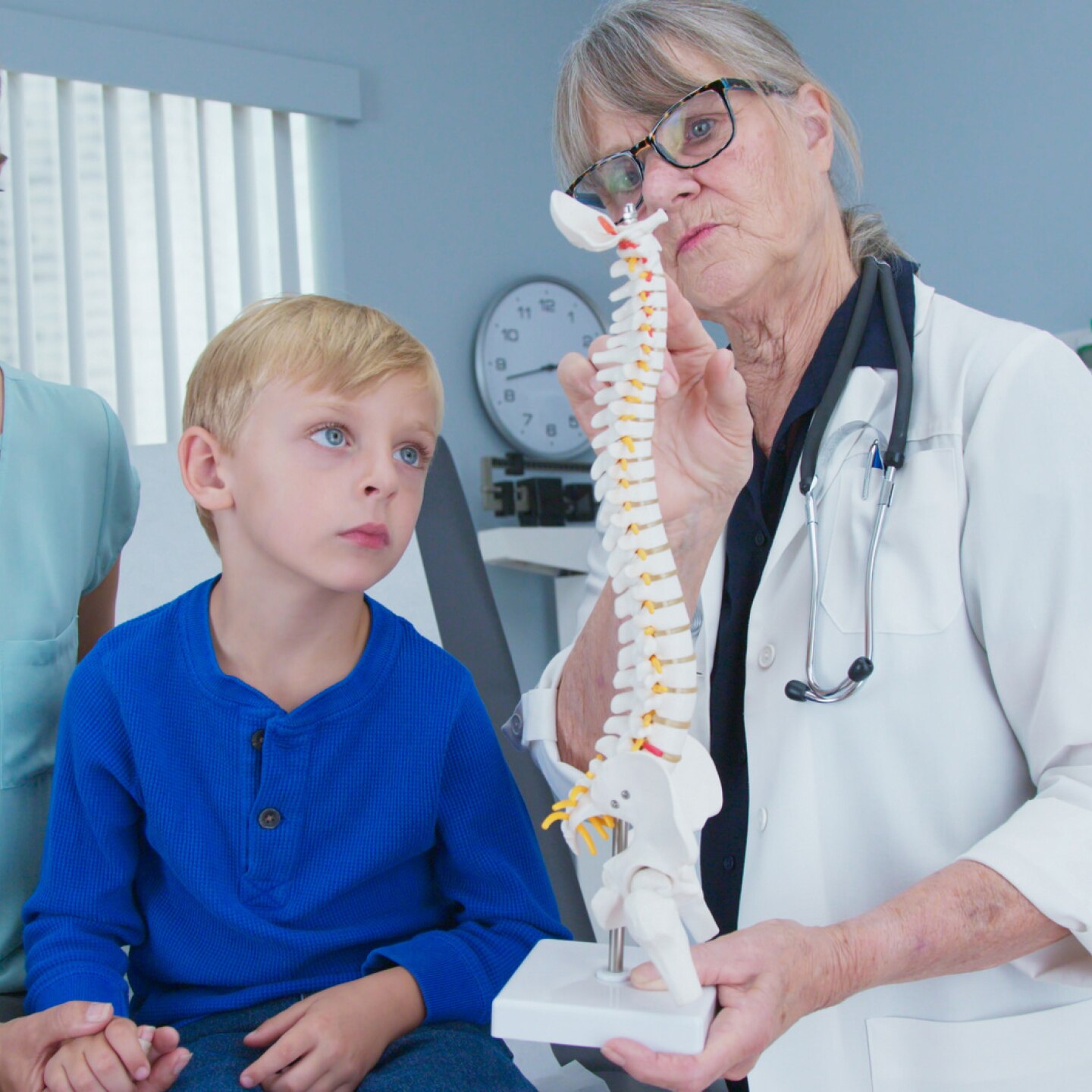 ärztin-zeigt-mutter-und-kind-ein-modell-der-wirbelsäule