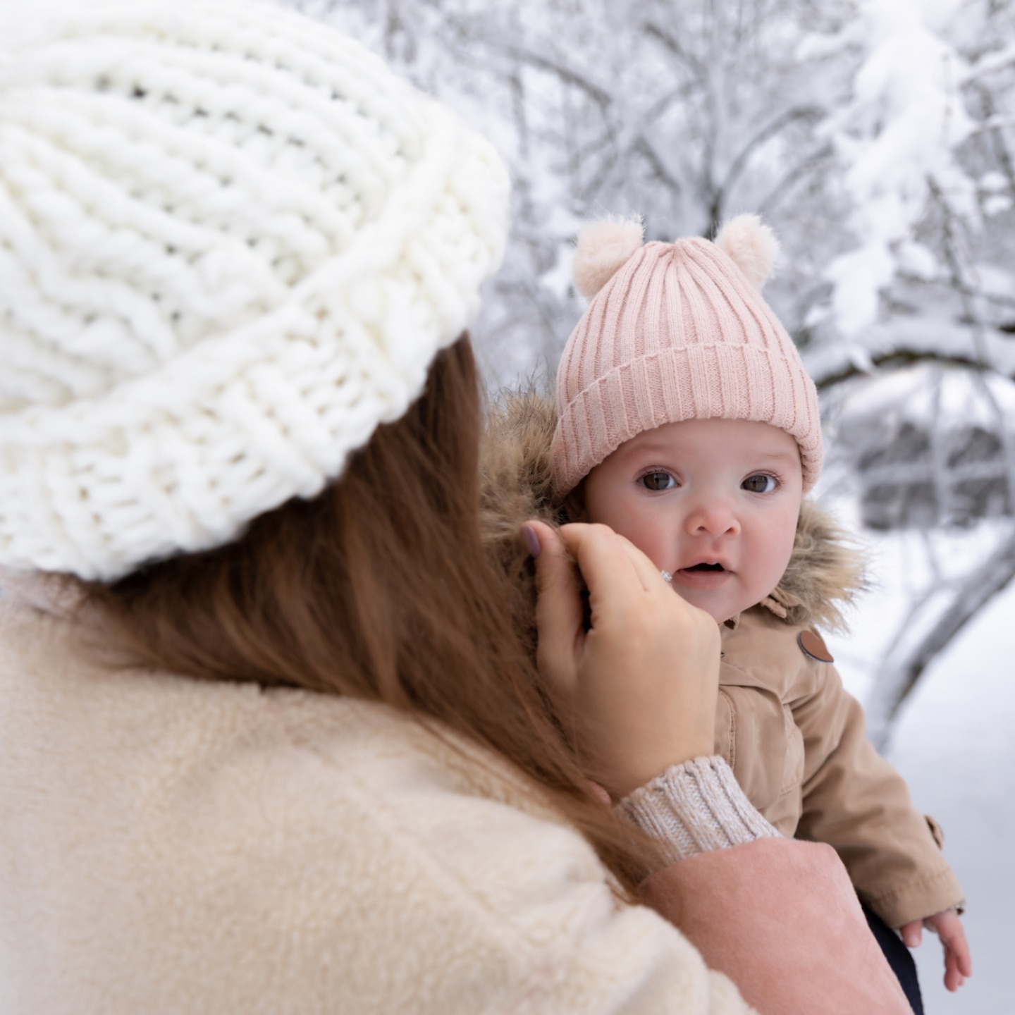 mutter-mit-dick-angezogenem-baby-draußen-im-schnee