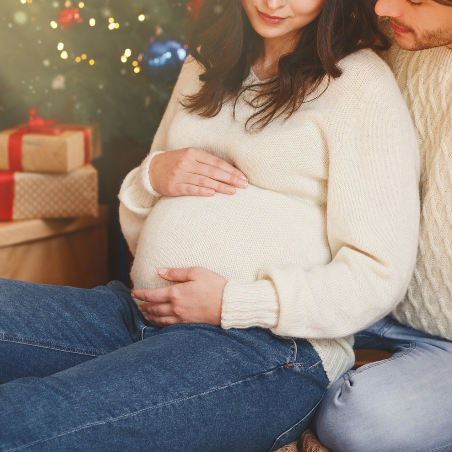 schwangere-und-ihr-partner-vor-einem-weihnachtsbaum-mit-geschenken