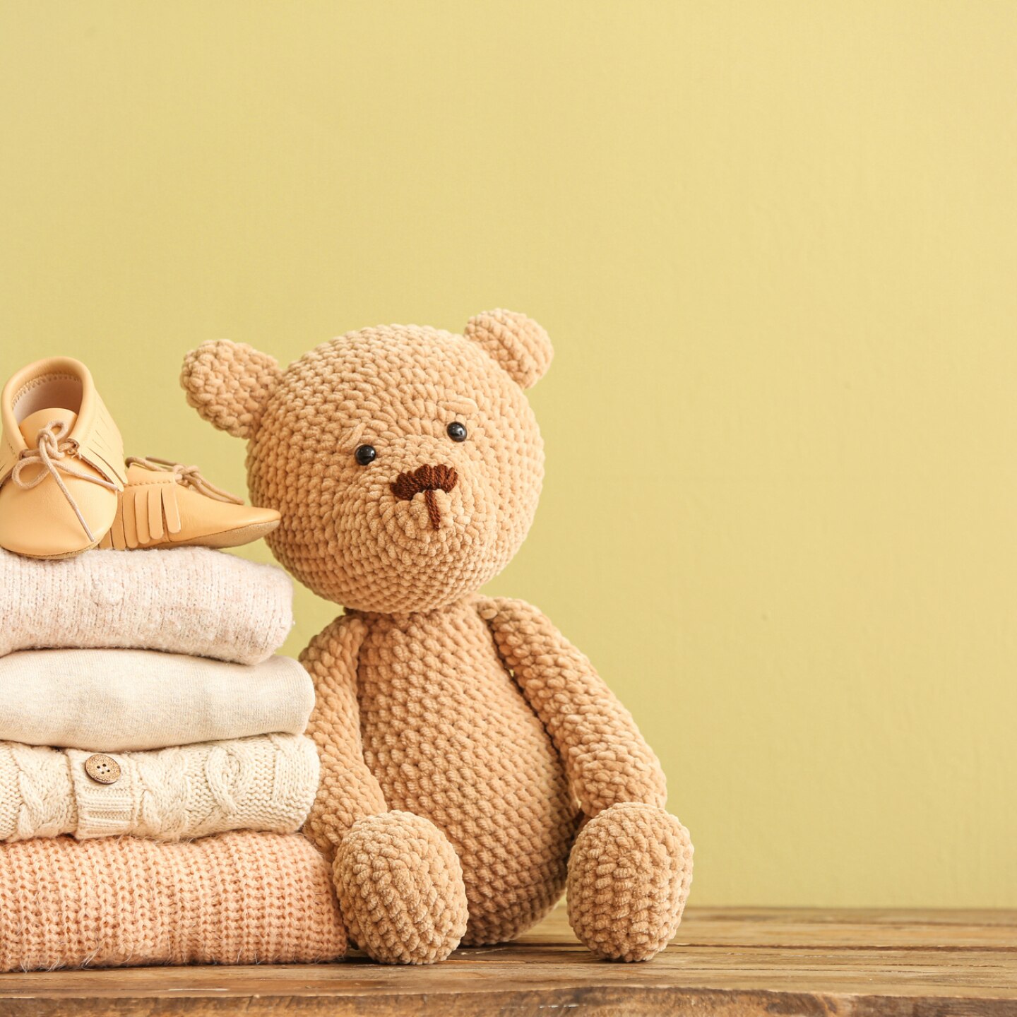 teddybär-neben-stapel-an-babykleidung
