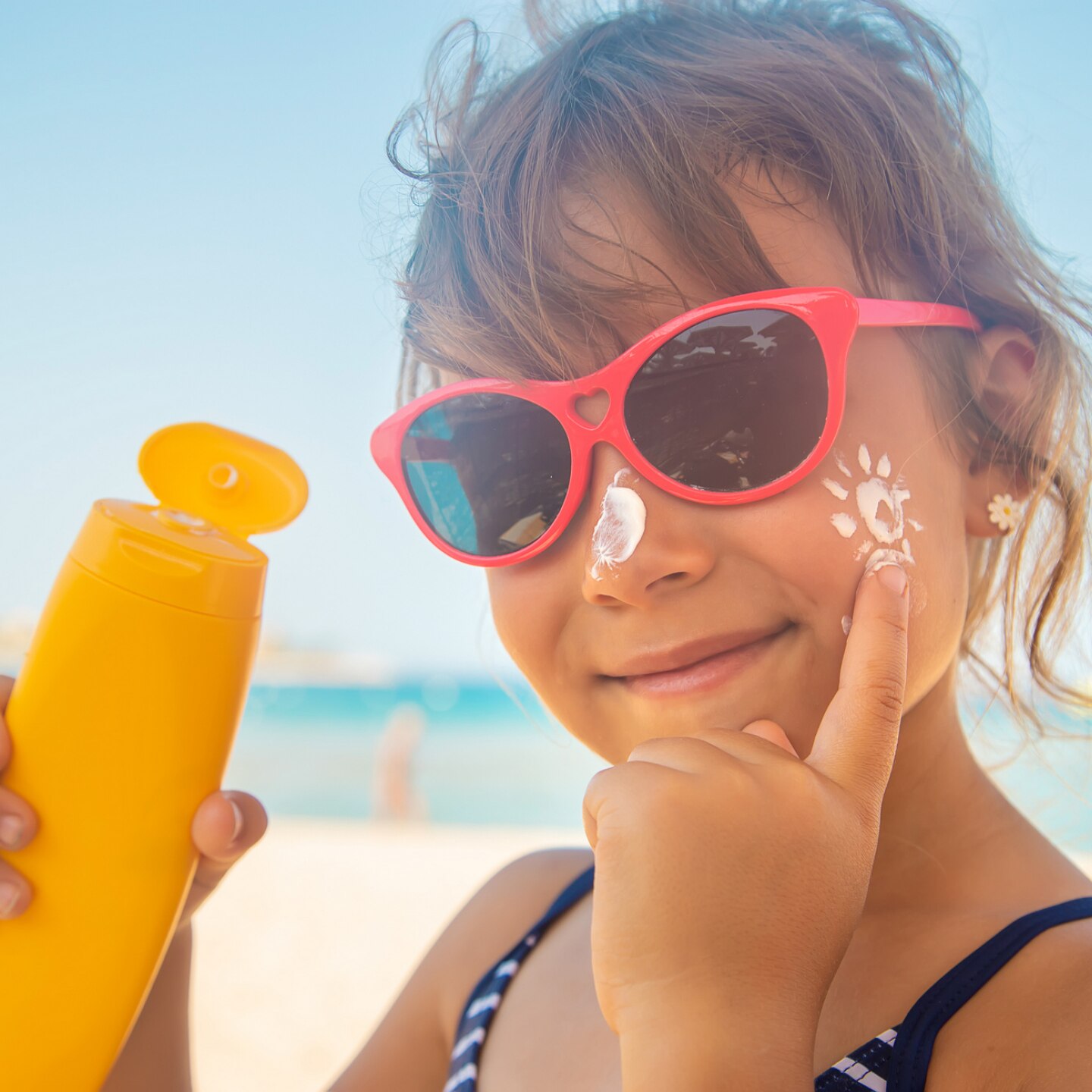 kleinkind-am-strand-mit-sonnencreme-in-der-hand