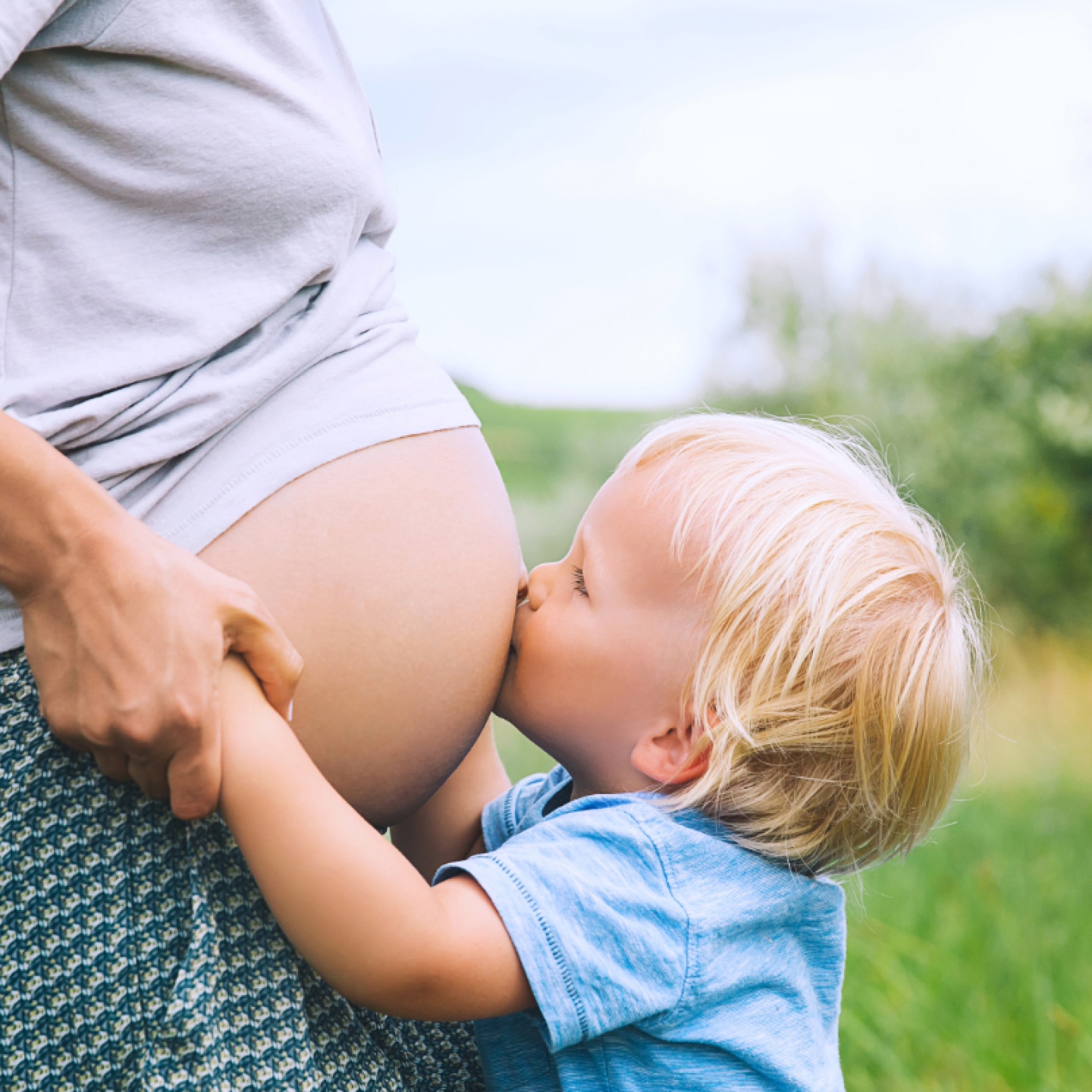 kleinkind kuesst babybauch seiner mama