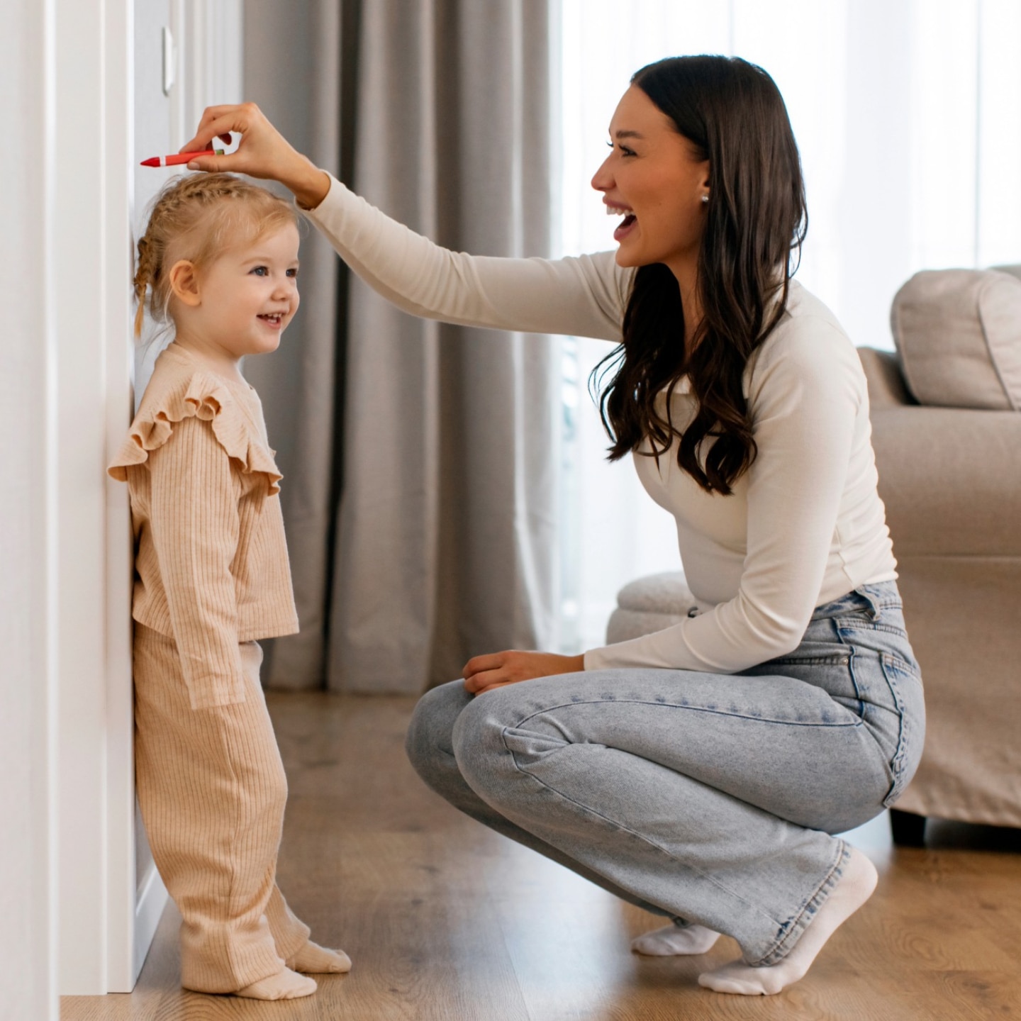 mama misst körpergröße ihrer tochter an der wand