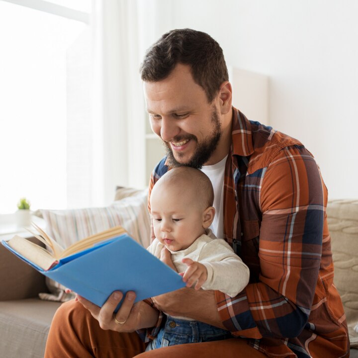 happy father and little baby boy with book at home