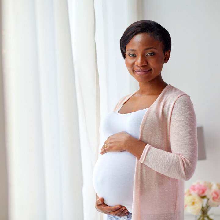 pregnant african american woman at home window