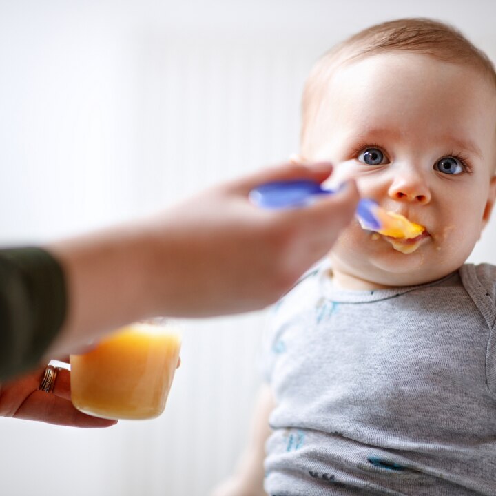 Mother feeds baby with fruit porridge