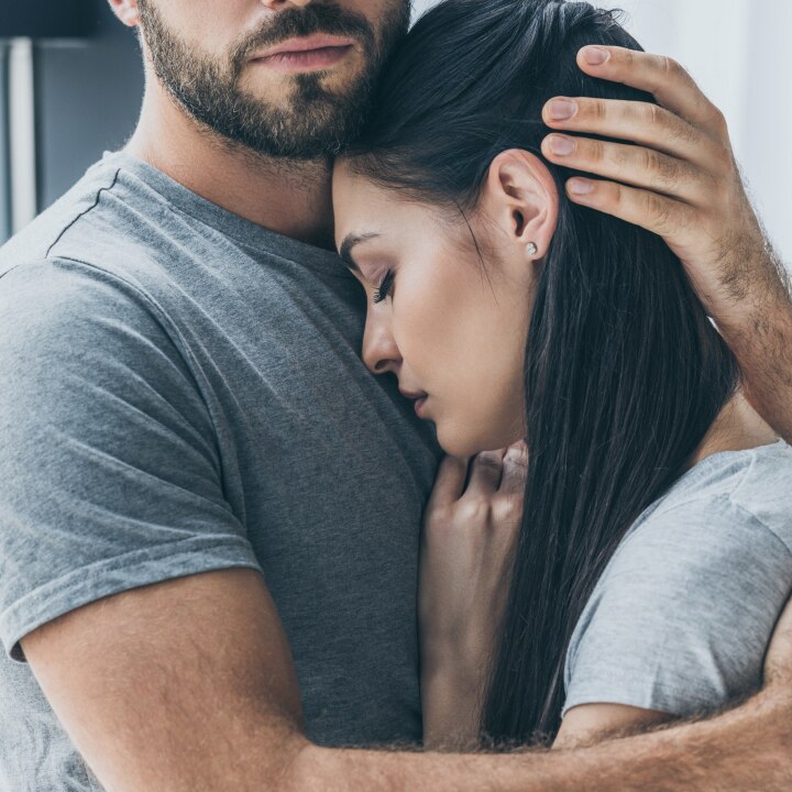 man hugging and supporting young sad woman