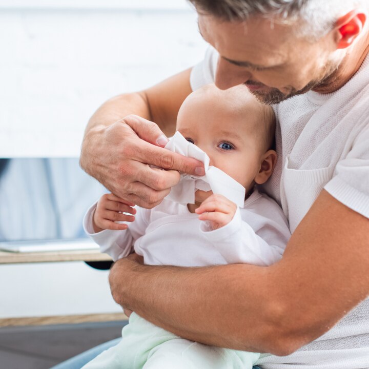 Vater putzt Baby die Nase