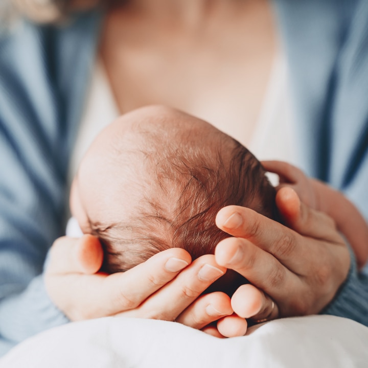 Frau hält den Kopf ihres Babys