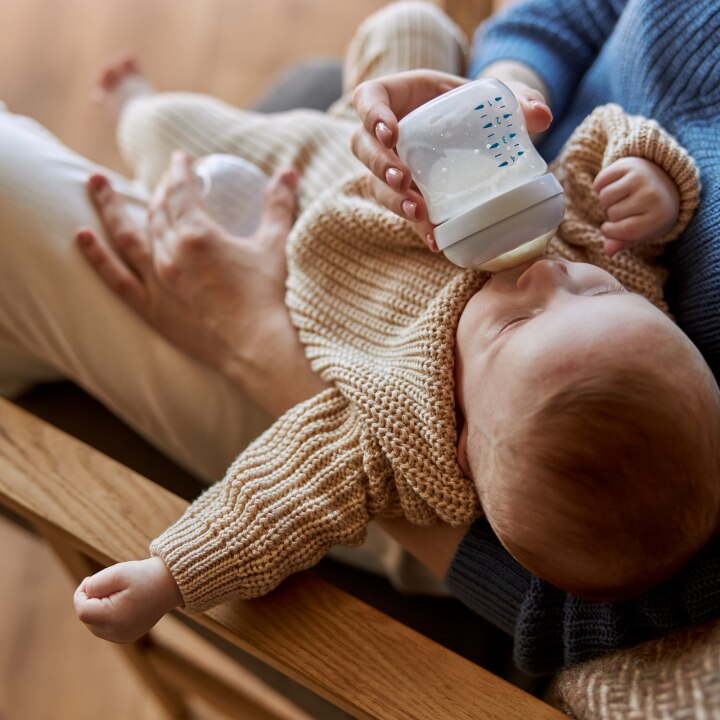 Mother feeding newborn baby from bottle with milk