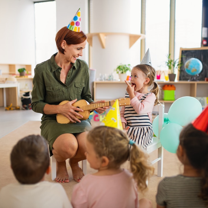 group of small nursery school children with teacher on floor indoors in classroom