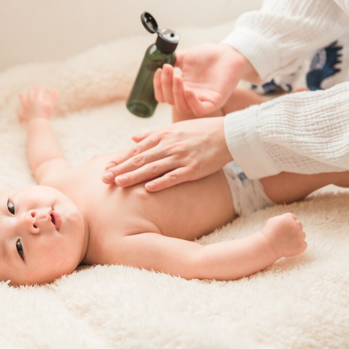 Mutter schmiert ihn mit Babyöl ein