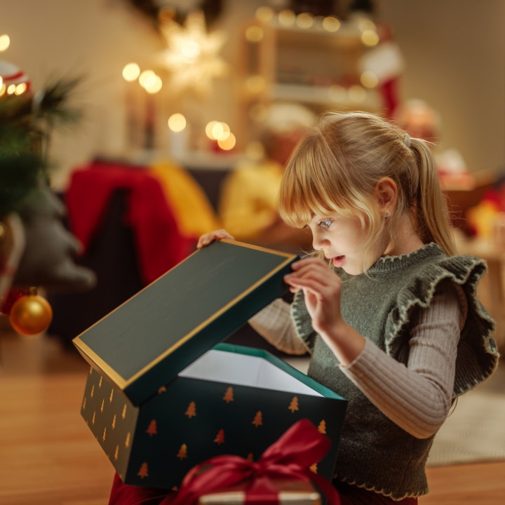 Little girl opening a mysterious Christmas present