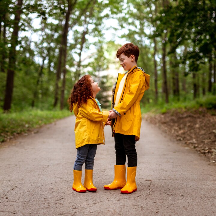 bruder-und-schwester-in-gelben-regenjacken-im-wald