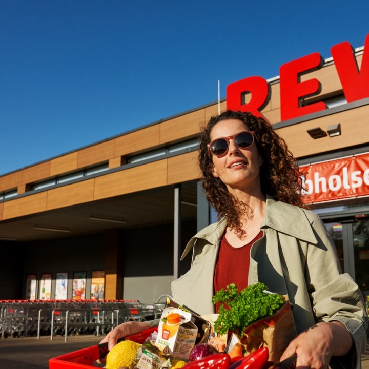 frau vor einem rewe supermarkt